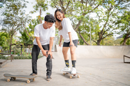 Two friends are actively mastering various skateboard tricks in a sunny park environmentの写真素材