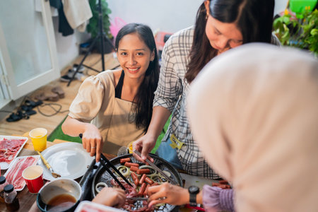 Friends are engaged in lively barbecue cooking, enjoying their time and creating memoriesの写真素材