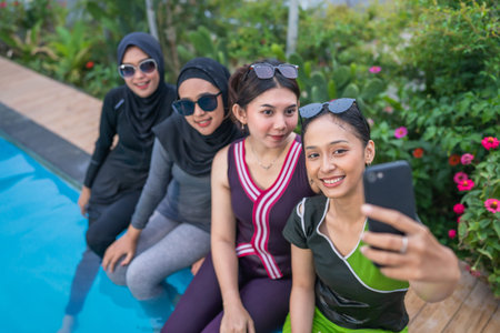 Friends pose for a fun selfie by the pool, surrounded by lush greenery on a carefree summer day