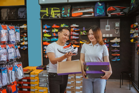 asian man and woman working at athletic footwear storeの写真素材