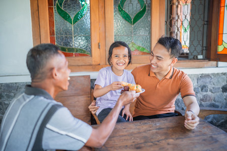 excited young kid offered snack by grandfather, family conceptの写真素材