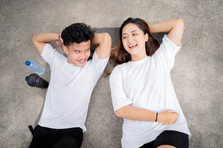 Two friends are fully enjoying a joyous moment while happily lying on the soft groundの写真素材
