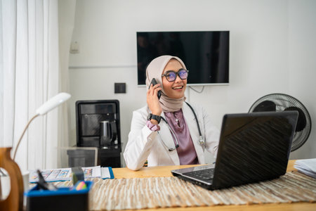 A medical doctor consulting over the phone from her modern and wellequipped office spaceの写真素材