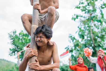 man enduring the load takes part in a betel nut climbing competition to celebrate Indonesias independenceの写真素材