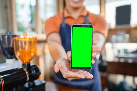 male barista hand showing blank screen phone with blurred backgroundの写真素材