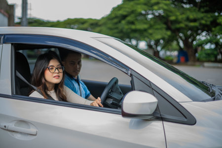 A young couple filled with joy is driving happily in a shiny silver car amidst lush greeneryの写真素材