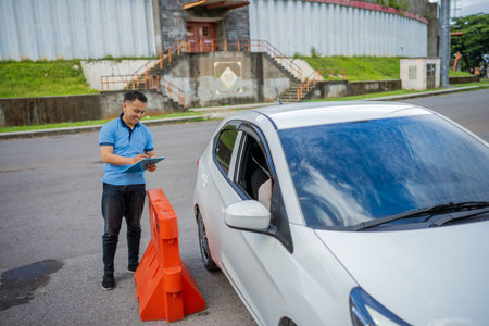 A traffic officer is assisting a driver at a roadside checkpoint that features safety barriersの写真素材