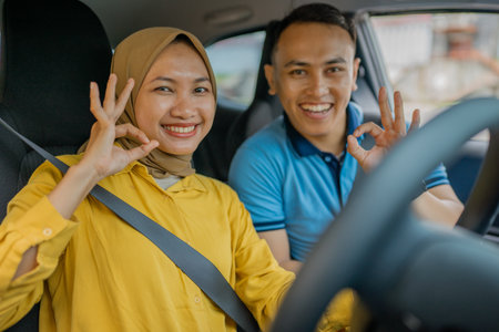 A joyful couple making cheerful gestures with each other while driving together on the roadの写真素材