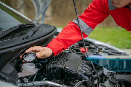 A mechanic inspects the engine coolant level in a cars engine bay for safety and functionの写真素材