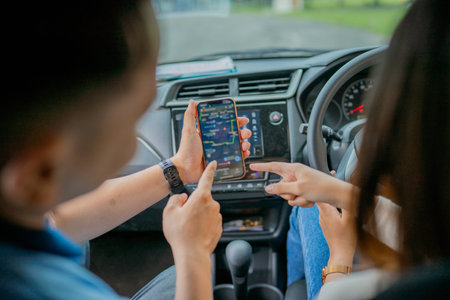 Two friends are looking at a smartphone while driving, planning their exciting journey