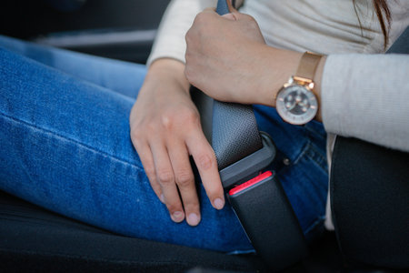 A woman fastening her seatbelt, highlighting the importance of road safety and responsible drivingの写真素材
