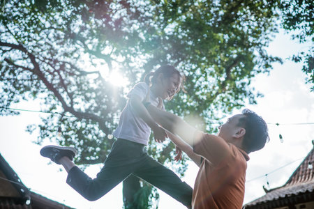 low angle view of happy asian daughter lifted up by her fatherの写真素材