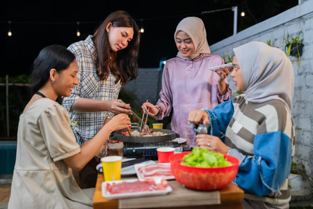 A group of friends joyously enjoying a fun time together while cooking in an outdoor BBQ settingの写真素材