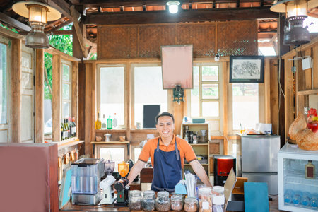 professional coffee shop male barista wearing apron standing behind counterの写真素材