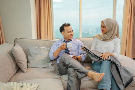 A couple joyfully shares a moment on a cozy couch, enjoying a stunning cityscape viewの写真素材