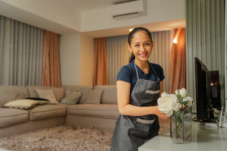 A cheerful and happy woman is arranging beautiful flowers in a stylish home interior spaceの写真素材