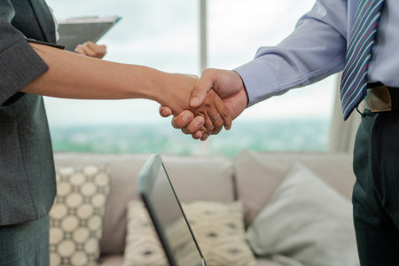 Business professionals engaged in a handshake while in a formal office environment settingの写真素材