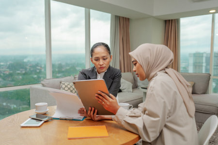 Businesswomen collaborating effectively on a project together in a modern contemporary workspaceの写真素材