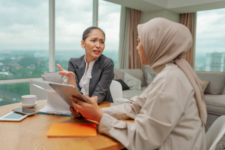 In a modern office, two businesswomen discuss their strategies and plans thoughtfullyの写真素材
