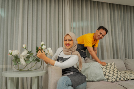 A stylish couple decorates their cozy living room with fresh flowers to create a welcoming vibeの写真素材