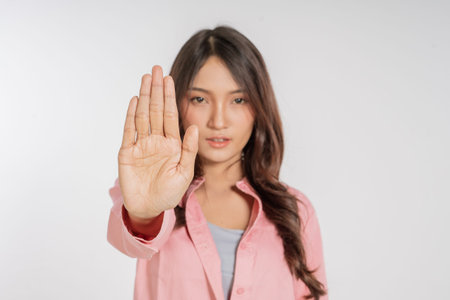 A confident woman is signaling to stop amidst a bright studio background that enhances her presence