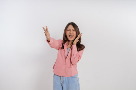 A cheerful young woman poses with peace signs, expressing happiness and positivity.の写真素材