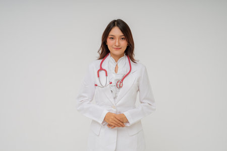 A smiling female doctor in a white coat and stethoscope, appearing confident and friendlyの写真素材
