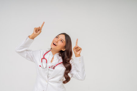 A cheerful doctor in a white coat points up with a stethoscope, embodying positivityの写真素材