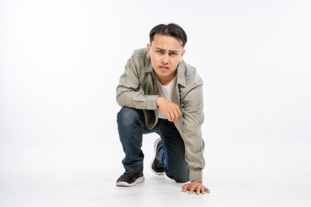 A trendy young man in a very stylish outfit is crouching with an intense and captivating lookの写真素材