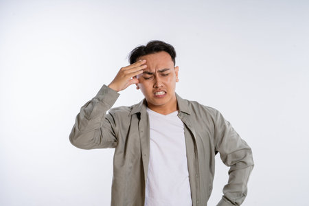 In a casual setting, a young man seems to be experiencing a headache, feeling quite stressed