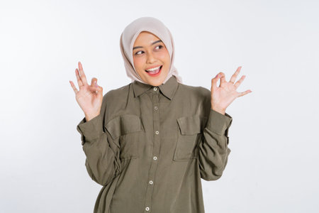 A happy young woman in a colorful hijab is joyfully showing peace signs while smiling brightly