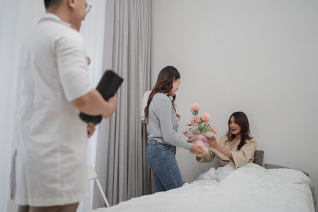 A patient joyfully receives beautiful flowers during a warm and heartfelt hospital visitの写真素材