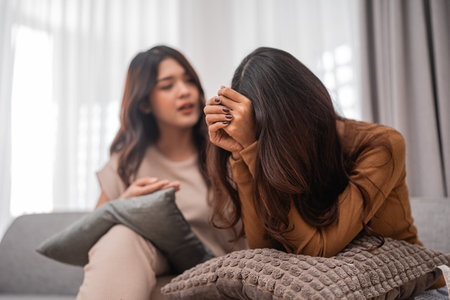 Two close friends have a heartfelt conversation while sitting comfortably together on a sofaの写真素材