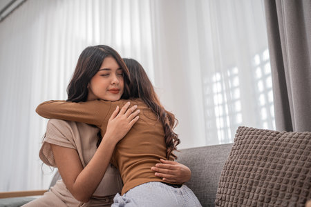 Two close friends warmly embrace each other in a cozy, bright sunlit setting, filled with joyの写真素材