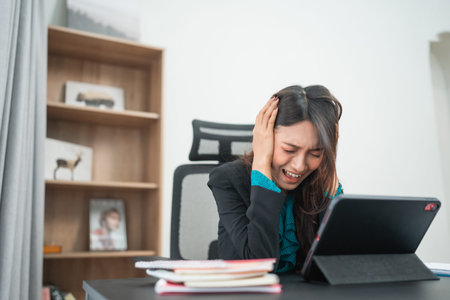 A very frustrated businesswoman feels completely overwhelmed while trying to work on her tablet