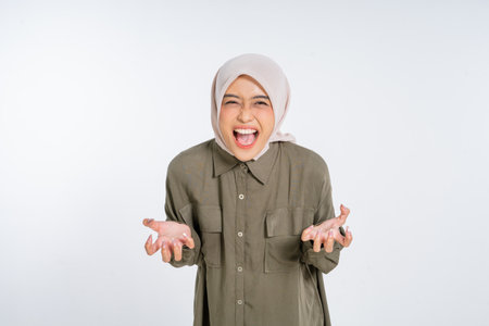 A young woman in a colorful hijab joyfully expresses herself with her hands raised highの写真素材
