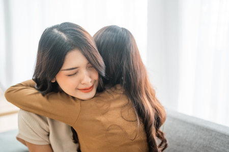 In a cozy, warm, and welllit setting, two women joyfully share a heartfelt and loving hugの写真素材