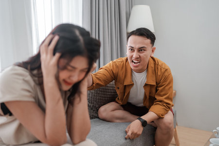 In a modern living room, a distressed woman and an angry man reveal deep emotional conflictの写真素材