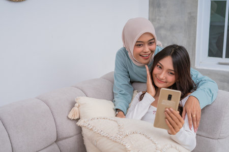 Friends are joyfully sharing a delightful moment together while scrolling on their smartphoneの写真素材