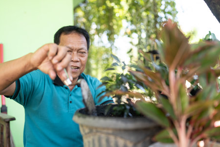 A joyful gardener tends to potted plants in a vibrant green environment full of lifeの写真素材