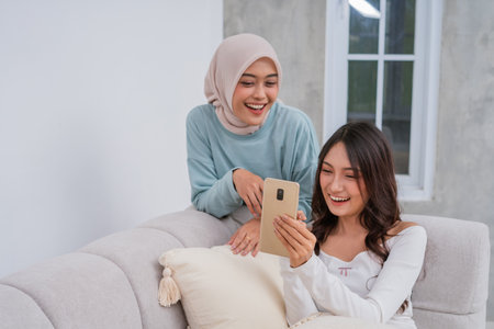 Two friends delight in a joyful moment shared together while happily using a smartphone deviceの写真素材