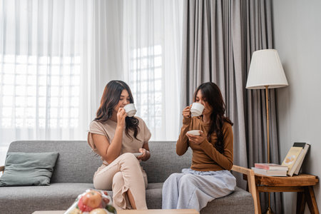 Two friends share a cozy moment over tea in a beautifully decorated living room.の写真素材