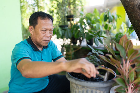 A man is carefully nurturing a variety of beautiful plants in a vibrant, lively gardenの写真素材