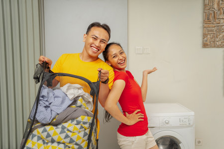 Joyful parents are happily enjoying a delightful laundry day while lovingly caring for their babyの写真素材
