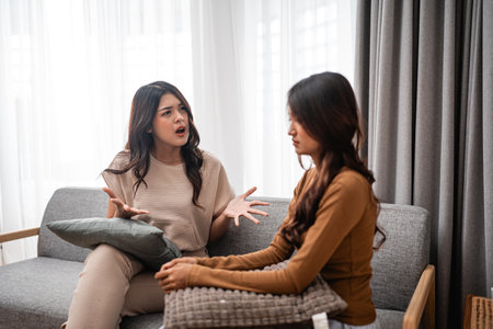 Two close friends are having a heartfelt discussion while sitting on a cozy sofaの写真素材