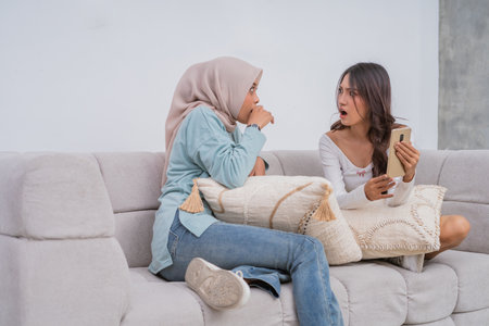 Two friends were happily engaged in a lively and animated conversation while sitting on the couchの写真素材