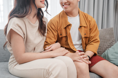 A couple is sharing a sweet and heartwarming moment while comfortably sitting on a stylish sofaの写真素材