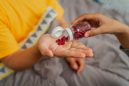 A caregiver assists a child needing medication in a nurturing, healing environmentの写真素材