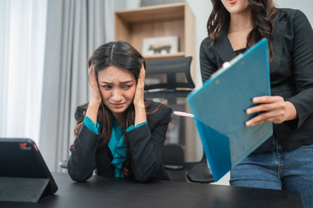 In a tense office scene, an overwhelmed employee faces immense pressure and stress at workの写真素材