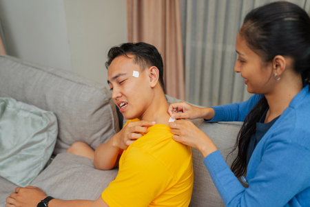A person assists a friend with injuries at home, showcasing care and friendship.の写真素材